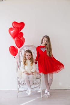 Beautiful little girl with red balloons in the shape of a heart