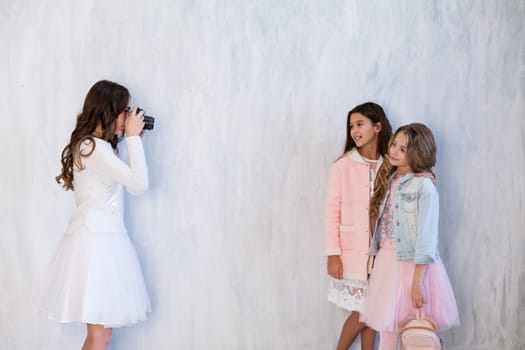 Three beautiful fashionable girls in white pink clothes at the photo shoot are photographed