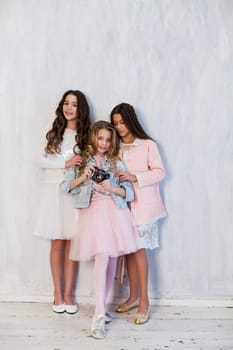 Three beautiful fashionable girls in white pink clothes at the photo shoot are photographed