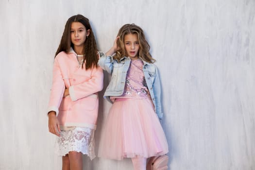 portrait of two beautiful girls in white pink clothes on a gray background