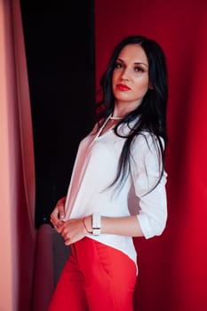 Portrait of a beautiful woman in a business suit in the office by the red wall