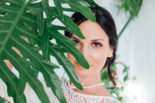 Portrait of a beautiful brunette woman with a green plant