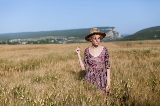 Beautiful fashionable woman blonde in a dress in a wheat field before harvest
