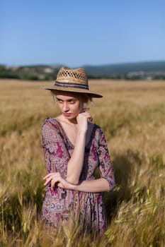 Beautiful fashionable woman blonde in a dress in a wheat field before harvest