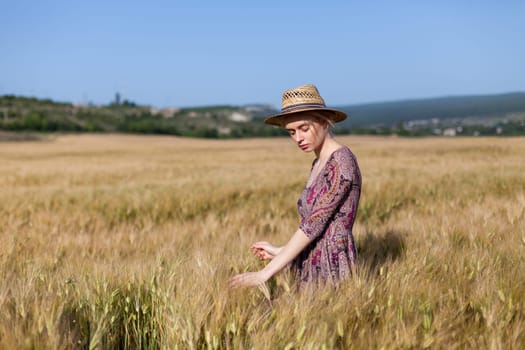 Beautiful fashionable woman blonde in a dress in a wheat field before harvest