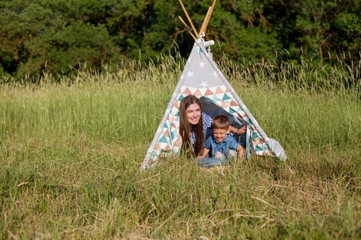 woman with her son on a picnic in a field near the forest