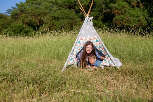 woman with her son on a picnic in a field near the forest