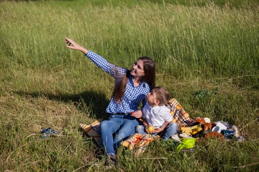 woman with her son on a picnic in a field near the forest