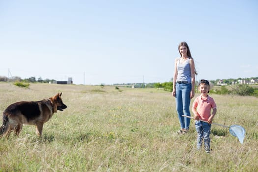 Beautiful woman with son plays with dog sheepdog on a walk