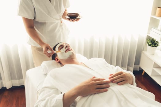 Serene ambiance of spa salon, man customer indulges in rejuvenating with luxurious face cream massage with modern daylight. Facial skin treatment and beauty care concept. Quiescent