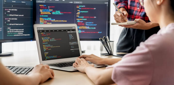 Two smart cooperative computer engineers working together as teamwork to solve program code while computer screen displayed program code. Laptop, web development, programer, java script . Burgeoning.