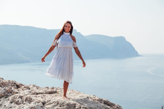 portrait of a woman with long hair in a dress on a cliff cliff by the sea