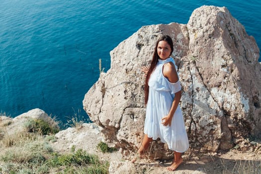 portrait of a woman with long hair in a dress on a cliff cliff by the sea