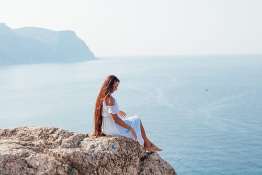 portrait of a woman with long hair in a dress on a cliff cliff by the sea