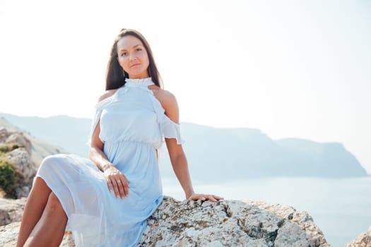 portrait of a woman with long hair in a dress on a cliff cliff by the sea