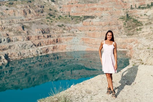 portrait of a woman with long hair in a dress on a cliff by the lake