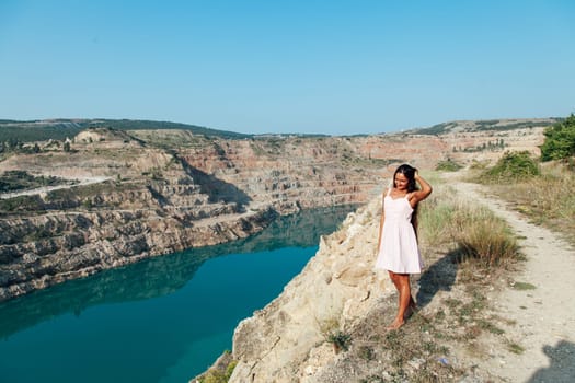 portrait of a woman with long hair in a dress on a cliff by the lake