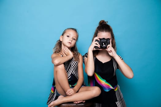 Portrait of two fashionable sisters girls with a camera