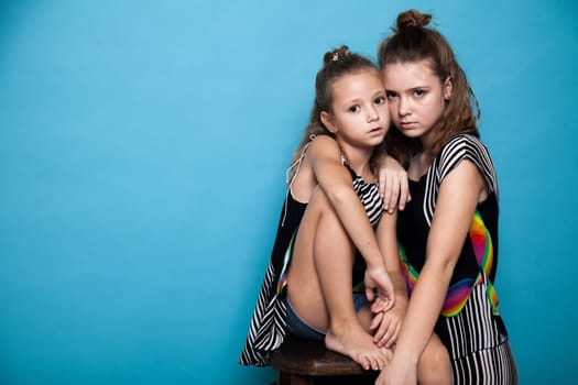 Portrait of two beautiful fashionable sisters girls on a gray background