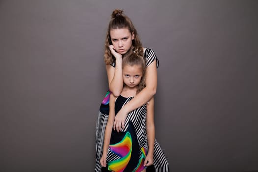 Portrait of two beautiful sisters girls on a gray background