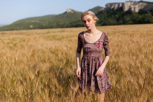 Portrait of a beautiful fashionable woman in a field before harvesting on the farm