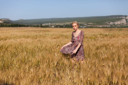 Portrait of a beautiful fashionable woman in a field before harvesting on the farm