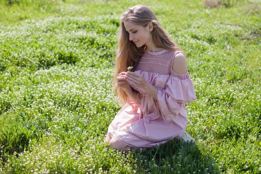 happy blonde woman in pink dress collects flowers in the flowering garden in spring