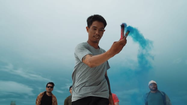 Group of multicultural hipster playing color flare at rooftop. Attractive street dancer holding colored smoke and perform break dance move to hip-hop music. Outdoor sport 2024. Endeavor.