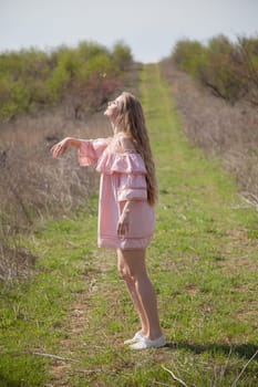 Beautiful woman in pink dress walks through the flowering garden in spring