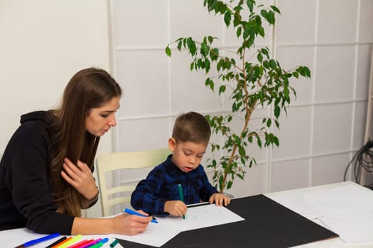 Mom and son learn to draw at table