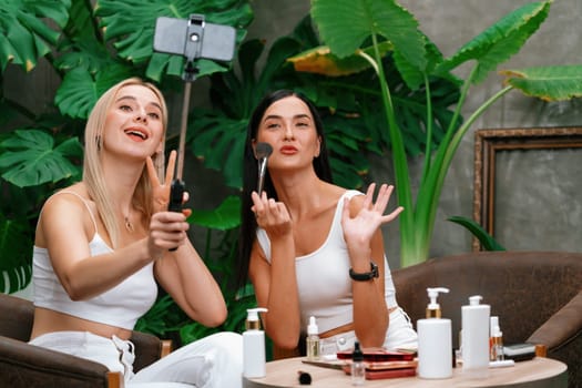 Two beautiful content creator making natural beauty and cosmetic tutorial on green plant garden video. Beauty blogger showing how to beauty care to social medial audience using selfie stick . Blithe