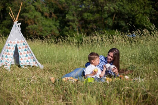 Beautiful woman with her beloved son on a picnic in the woods