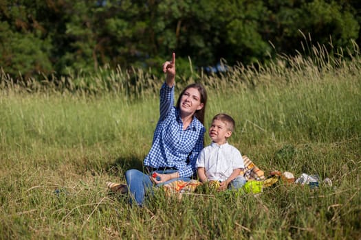 Beautiful woman with her beloved son on a picnic in the woods