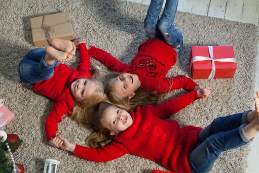 Three little girl girlfriends open gifts at the Christmas tree new year winter