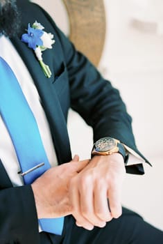Groom fastens the watch on his hand. Cropped. Faceless. High quality photo