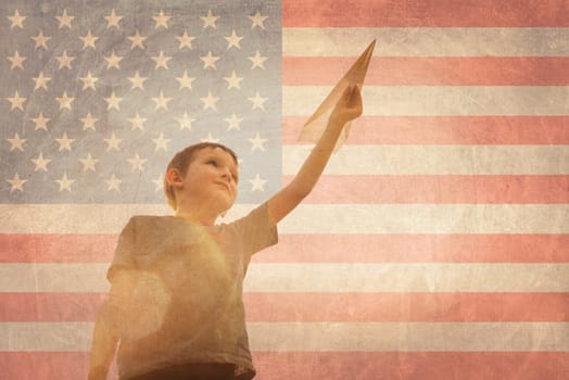 Little boy launches a paper plane into the air on the flag of america background. Child launches a paper plane with pride.