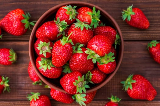 Fresh strawberries in a bowl on wooden table. Strawberry in a Bowl. Top view.