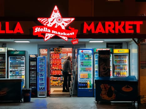 Refrigerators with drinks stand near a small shop. Caption: Stella marketi. High quality photo