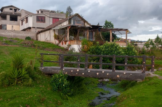 landscape of a rural house in Ecuador made with wood and reeds next to a bridge that passes under a small river. High quality photo