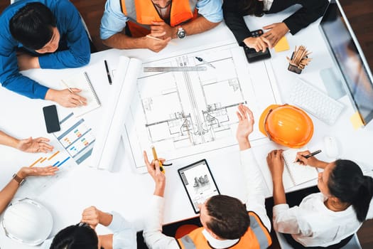 Top view banner of diverse group of civil engineer and client working together on architectural project, reviewing construction plan and building blueprint at meeting table. Prudent