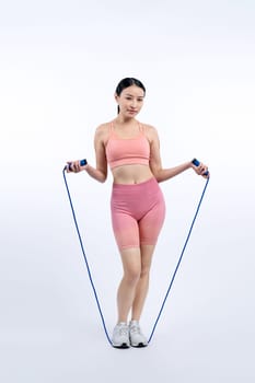 Young energetic asian woman in sportswear with jumping or skipping robe posing portrait in studio shot on isolated background. Cardio exercise tool and healthy body care lifestyle. Vigorous