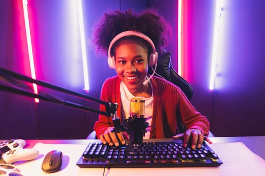 Host channel of gaming streamer, African girl taking, typing with Esport skilled team player and viewers online game in neon color lighting room. Concept of cybersport indoor activities. Tastemaker.