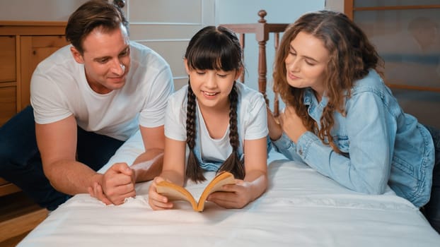 Bedtime story with childhood storytelling, mom and dad reading a fantasy book together to their little young girl in cozy and comfortable bedroom. Modern family happy time. Panorama Synchronos