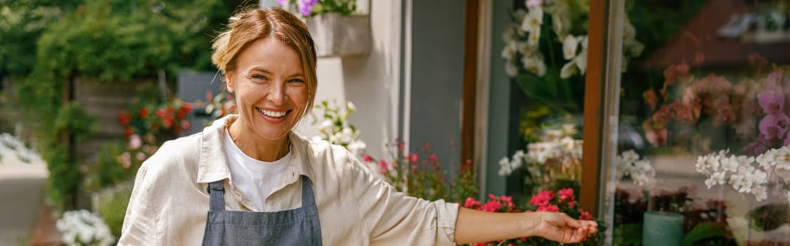 Woman florist small business owner standing in floral store and waiting for client with houseplants