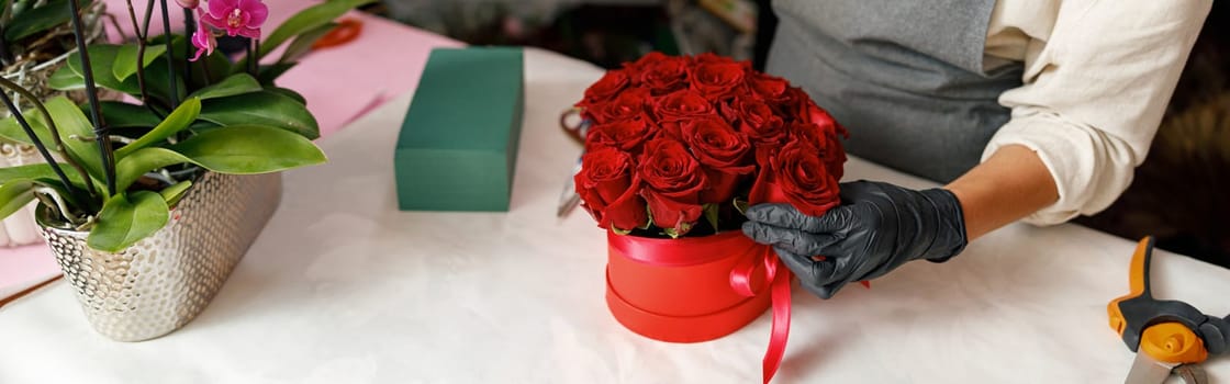 Female decorator creating beautiful composition at table. Lifestyle flower shop