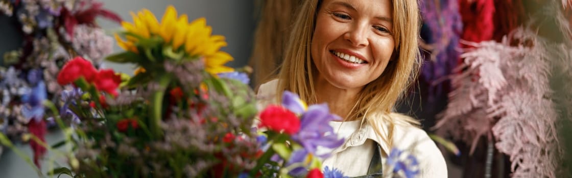 Female decorator creating beautiful bouquet at table. Lifestyle flower shop