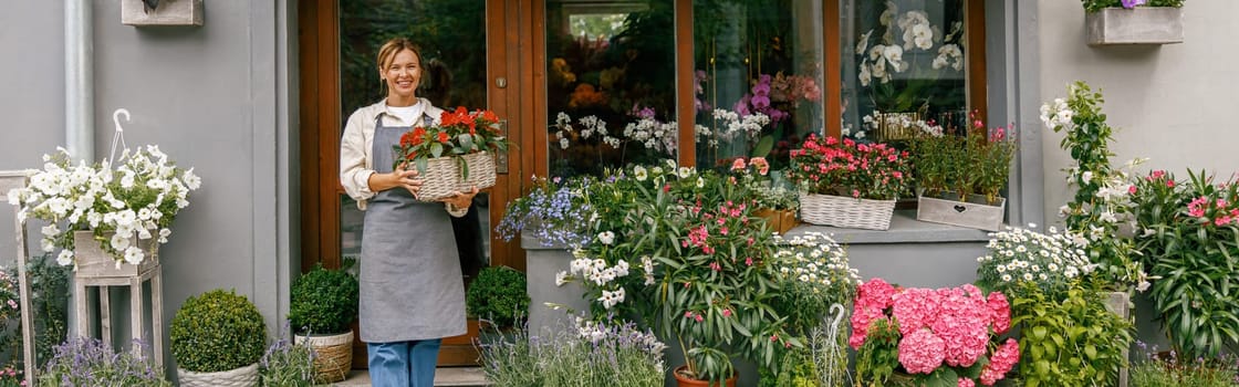 Woman florist small business owner standing in floral store and waiting for client with houseplant