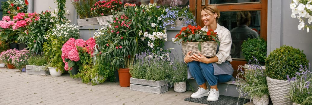 Woman florist small business owner sitting in floral store and waiting for client with houseplants