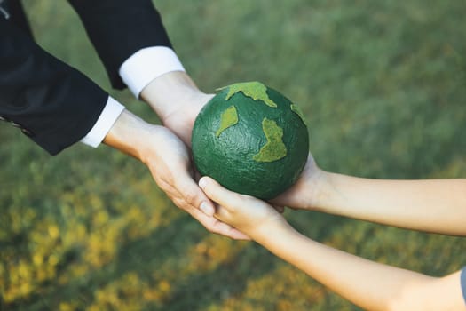 Businessman hand giving Earth globe to little boy as Earth day concept as corporate social responsible to contribute greener environmental protection for sustainable future generation. Gyre