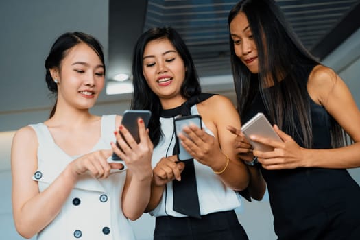 Three women friends having conversation while looking at mobile phone in their hands. Concept of social media, gossip news and online shopping. uds